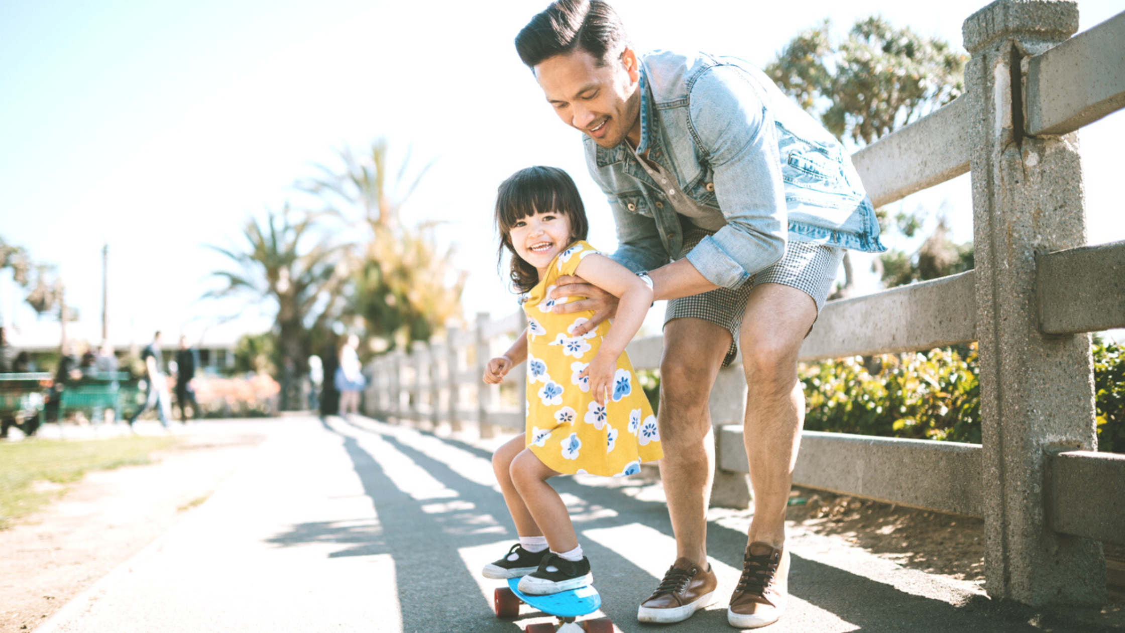 9 Summertime Activities for You and Your Kids Blog Featured Image - MHA of WNY A father took his daughter to the park to practice skateboarding as one of their summertime activities.