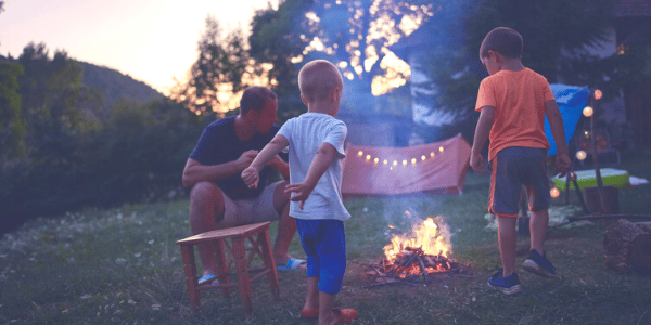 A father and his kids participating in backyard camping as one of their outdoor summertime activities.
