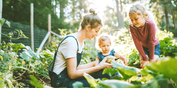 A mother and her kids participating in gardening as one of their summertime activities.