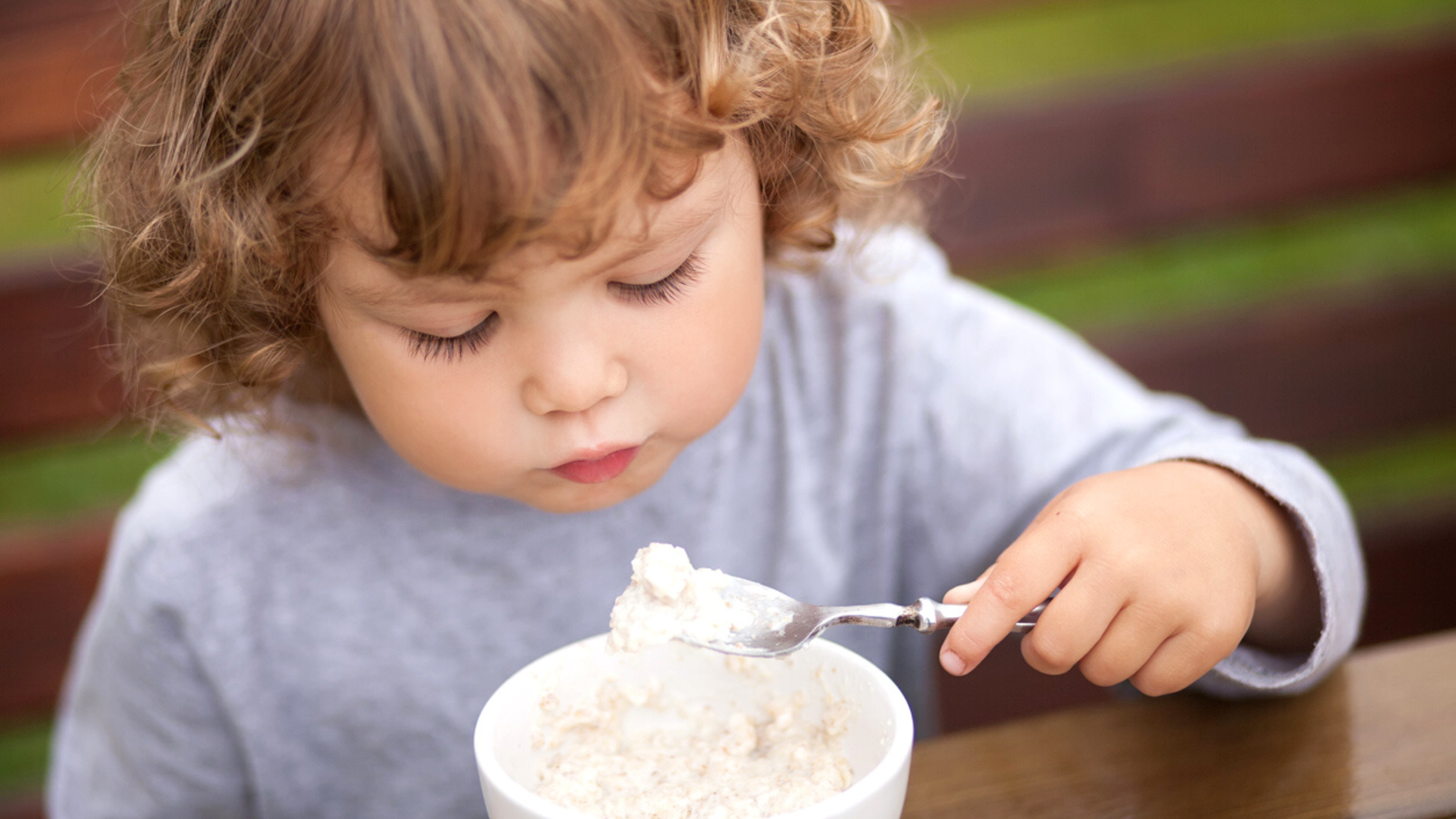 Fun and Healthy Snacks Ideas Kids Will Love This Summer - MHA of WNY Featured Image A young girl having her oatmeal outside the house.