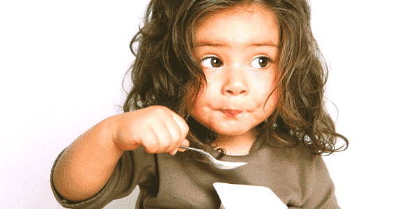 Portrait of a young girl eating yogurt.