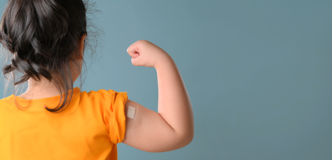 A little girl is showing off her bandage knowing that kids and vaccinations go together.