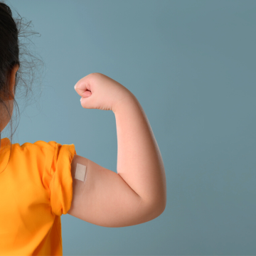A little girl is showing off her bandage knowing that kids and vaccinations go together.