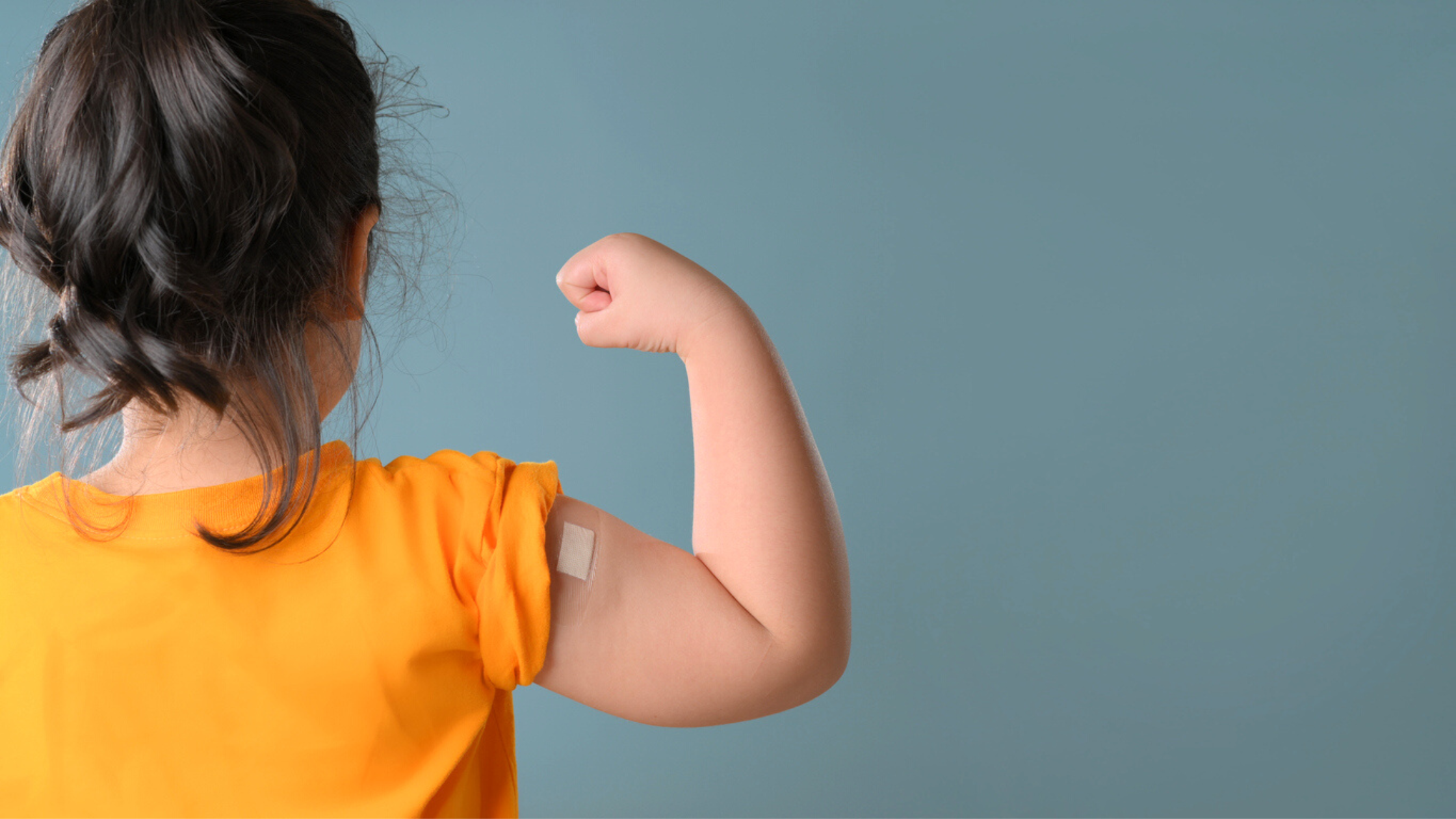 A little girl is showing off her bandage knowing that kids and vaccinations go together.