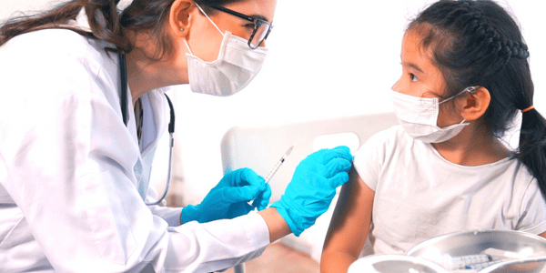 A female doctor knows kids and vaccinations can be scary so she is reassuring the little girl.
