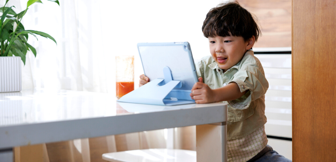 A little boy enjoying his screen time while using the tablet.