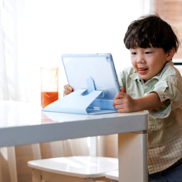 A little boy enjoying his screen time while using the tablet.